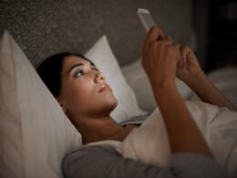 Saying goodnight to my love. A young woman sending a text message while in bed.