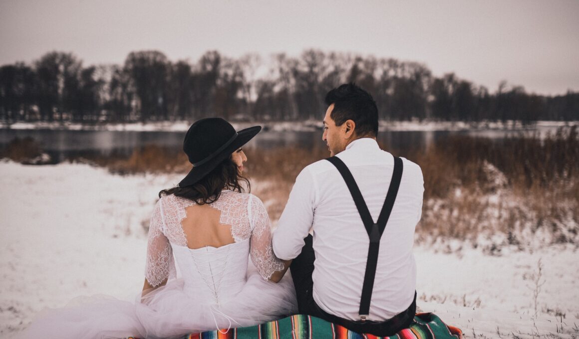 Mexican bride and groom in wedding clothes and suspenders sit on the snow in winter