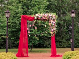 A wedding bright red arch decorated with flowers. Beautiful wedding decor for newlyweds.