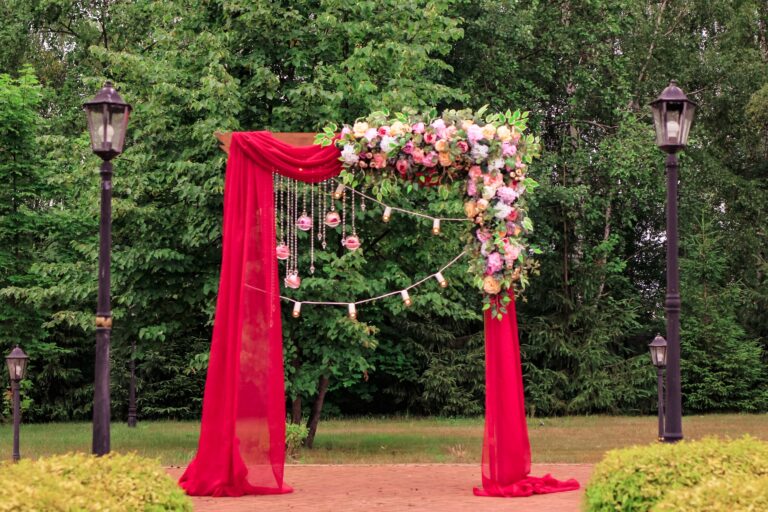 A wedding bright red arch decorated with flowers. Beautiful wedding decor for newlyweds.