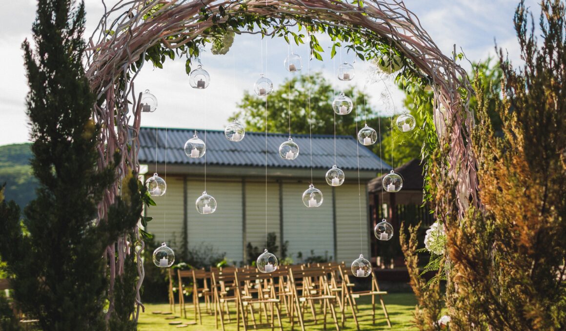 Evening wedding ceremony in garden, arch with white branches, brown wooden chairs