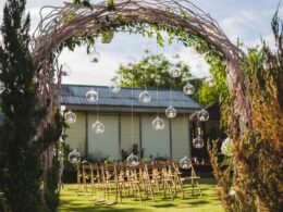 Evening wedding ceremony in garden, arch with white branches, brown wooden chairs