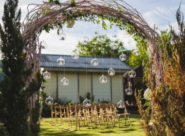 Evening wedding ceremony in garden, arch with white branches, brown wooden chairs
