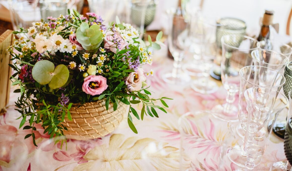 Flowers decorating the centerpieces with luxury cutlery on the tables of a wedding hall.