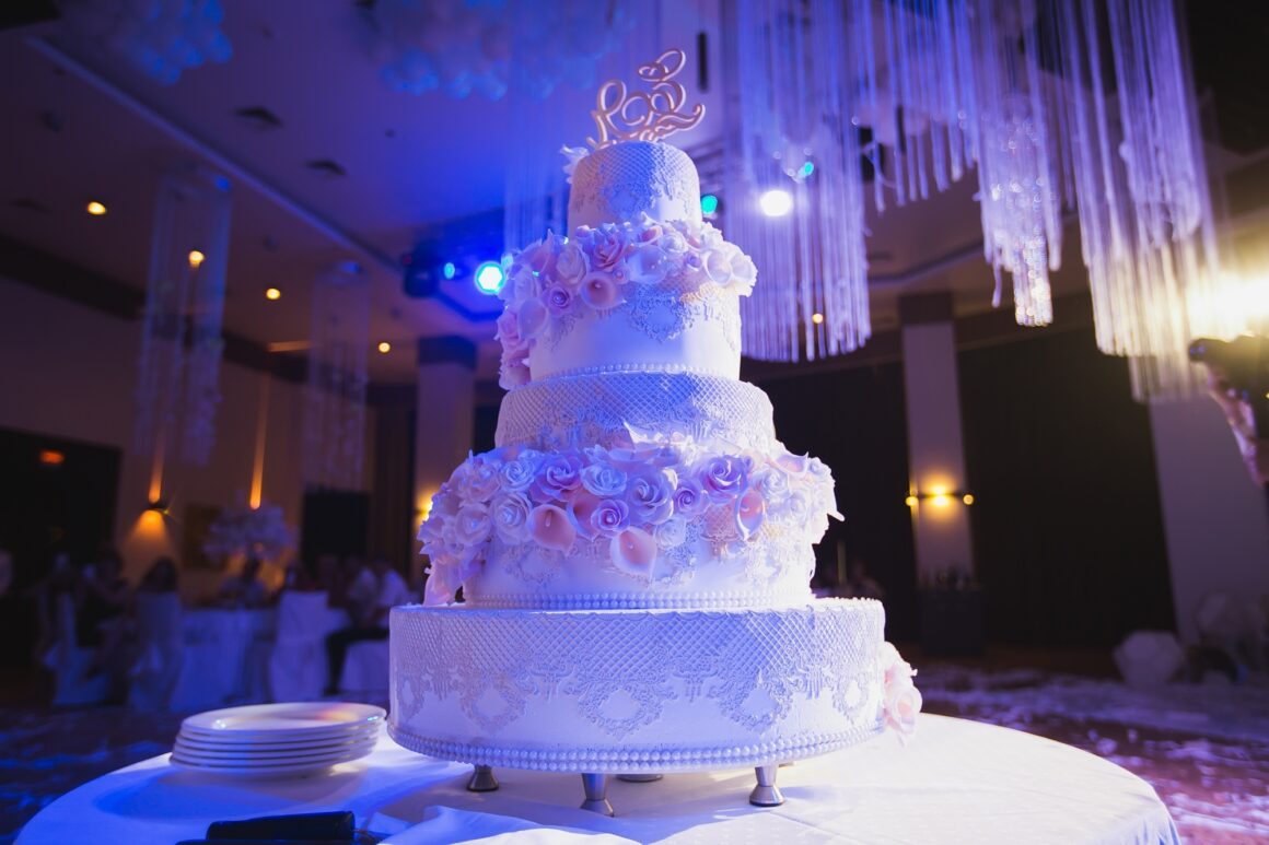 big white wedding cake with pink roses on a white table