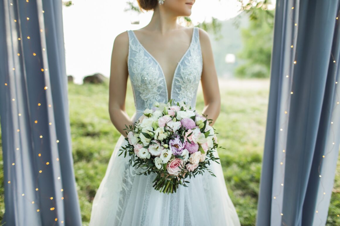 Bride holding in hands small wedding bouquet in pastel colors. Light pink and white roses