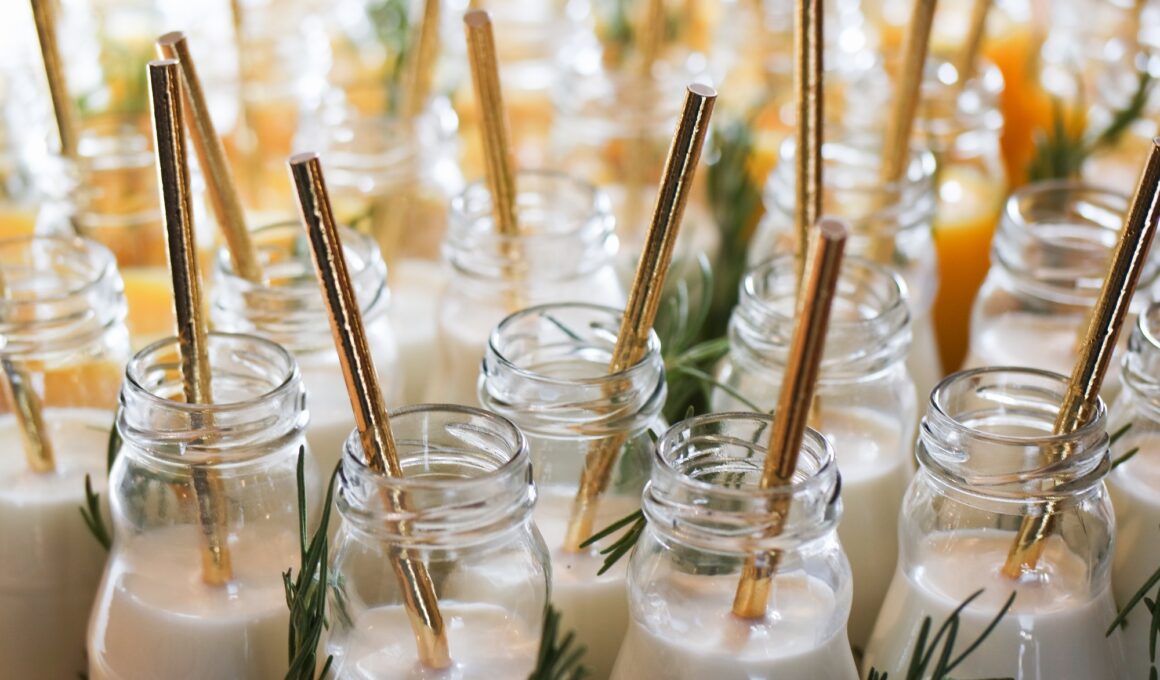 Milk in reusable glass bottles with golden drinking straws at the wedding party.