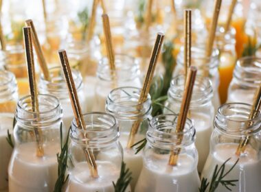 Milk in reusable glass bottles with golden drinking straws at the wedding party.