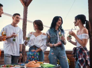 It's my birthday. Cheerful young people chatting and drinking cocktails at a rooftop party