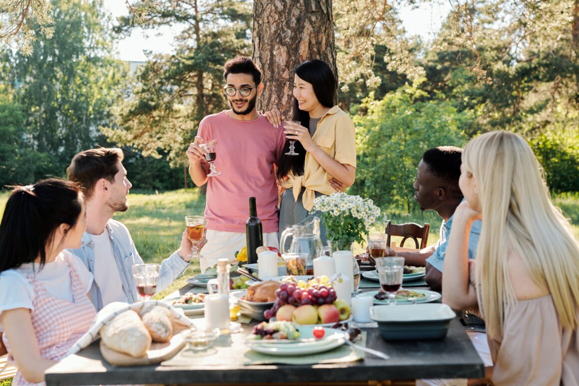 Young intercultural couple with glasses of red wine announcing their engagement