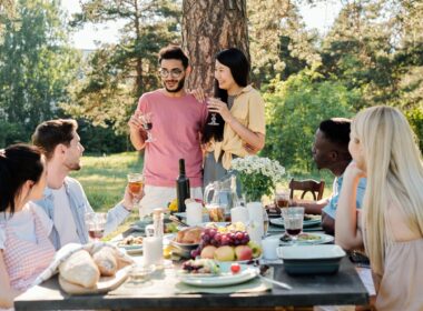 Young intercultural couple with glasses of red wine announcing their engagement