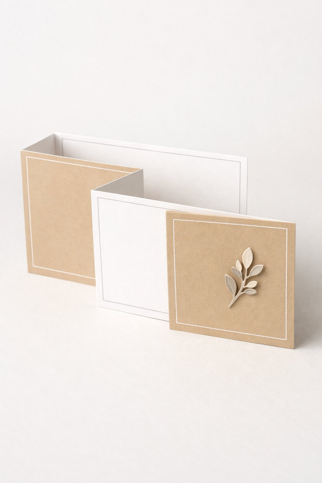 Ultra realistic product photo of a handmade double Z fold card with a clean minimalist design, shown partially open to clearly display the double Z fold structure, white and warm beige cardstock, thin geometric line frames in light grey (no wording), small neutral botanical sprig cutout as the only focal element, crisp folds, matte paper texture, photographed from a slight top-front angle on a plain light background with soft studio lighting, no text, no logo, no watermark, high clarity, sharp focus.