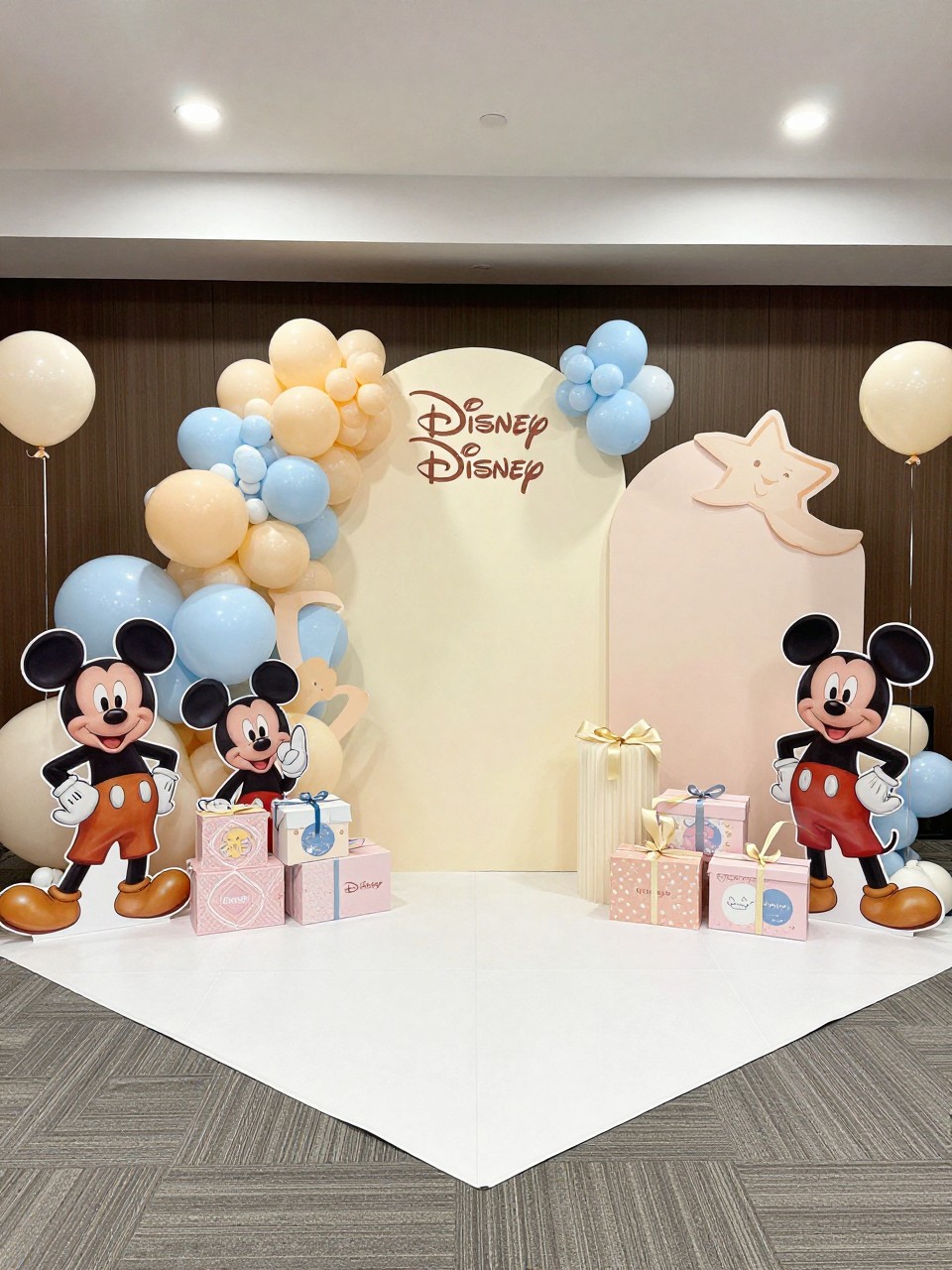 A decorated photo booth area with life-sized Disney character cutouts and baby shower decorations including balloons and gifts.