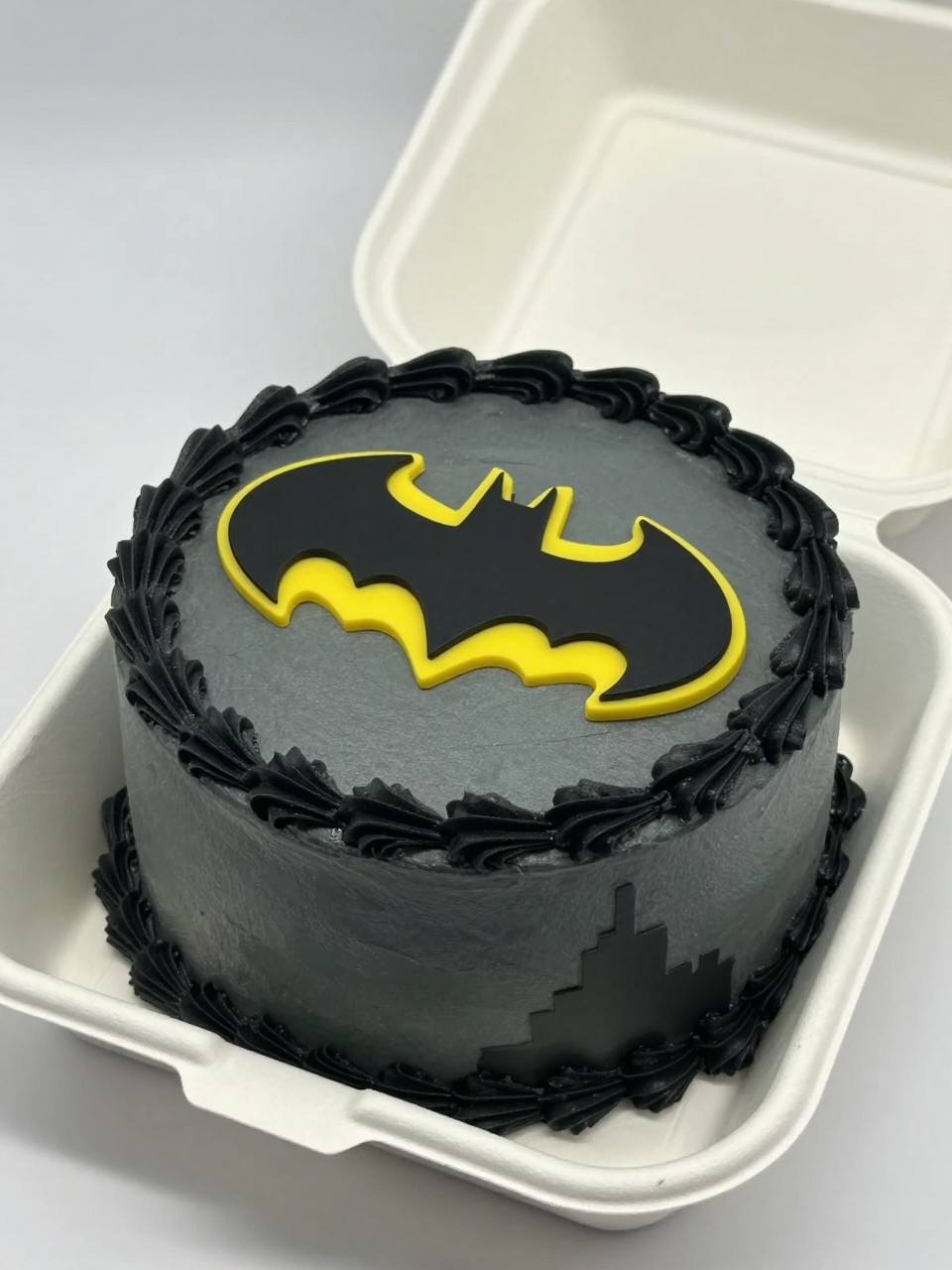 Image Prompt:
A Batman themed bento cake in an open white cake box, smooth dark gray frosting, glowing yellow bat signal design shining from one side of the cake, subtle black city shadow details, neat black piped border, modern superhero styling, realistic close-up bakery photography, soft studio light, no people, no hands, no faces, (no watermarks on images)