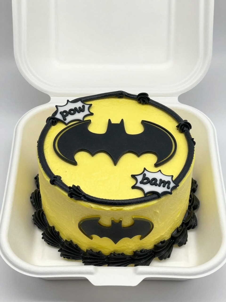 Image Prompt:
A comic style Batman themed bento cake inside an open white cake box, bright yellow and black frosting accents, Batman logo on top, comic style speech bubble details with words like “pow” and “bam,” bold black outlines, playful superhero styling, realistic close-up bakery photography, no people, no hands, no faces, (no watermarks on images)