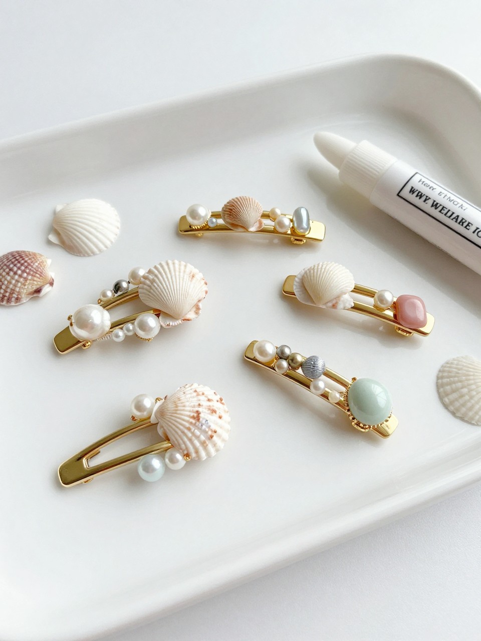 Detailed Image Prompt:
A stylish summer craft photo of handmade seashell hair clips, gold and silver hair clips decorated with tiny shells, pearls, small beads, and soft pastel accents, placed on a white vanity tray with extra shells and jewelry glue nearby, beachy teen accessory style, bright natural light, no people, no faces, no text, no watermark on images.