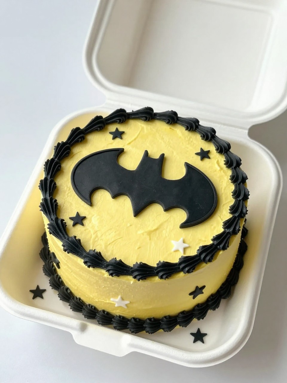 Image Prompt:
A fun Batman themed bento cake inside an open white bento cake box, smooth yellow frosting, bold black Batman logo centered on top, tiny black and white star details scattered around the edges, neat black piped border, cheerful superhero birthday styling, realistic bakery photography, bright natural light, no people, no hands, no faces, (no watermarks on images)