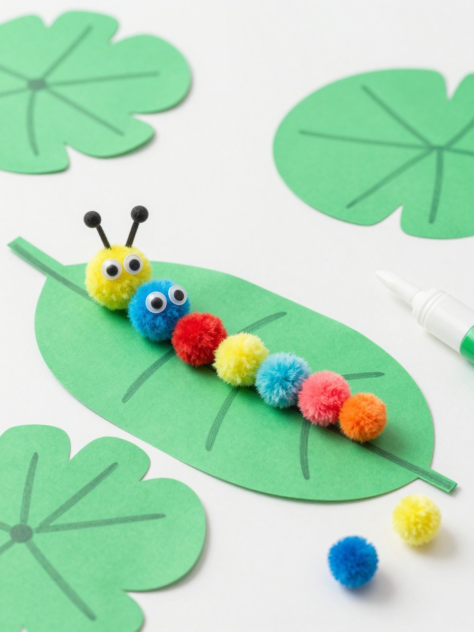 Detailed Image Prompt:
A sweet toddler craft photo showing colorful pom-pom caterpillars on large green paper leaves, soft pom-poms glued in a row with googly eyes, paper leaves with simple crayon lines, glue and extra pom-poms nearby, bright summer garden craft style, clean tabletop, no people, no faces, no text, no watermark on images.