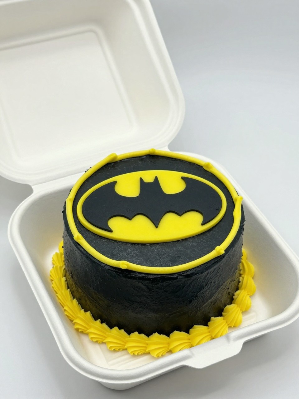 Image Prompt:
A creative Bat man themed bento cake inside an open white bento cake box, small round cake with smooth black buttercream frosting, large yellow Batman logo centered on top, neat yellow piped border, clean superhero birthday styling, soft natural light, realistic editorial bakery photography, no people, no hands, no faces, (no watermarks on images)