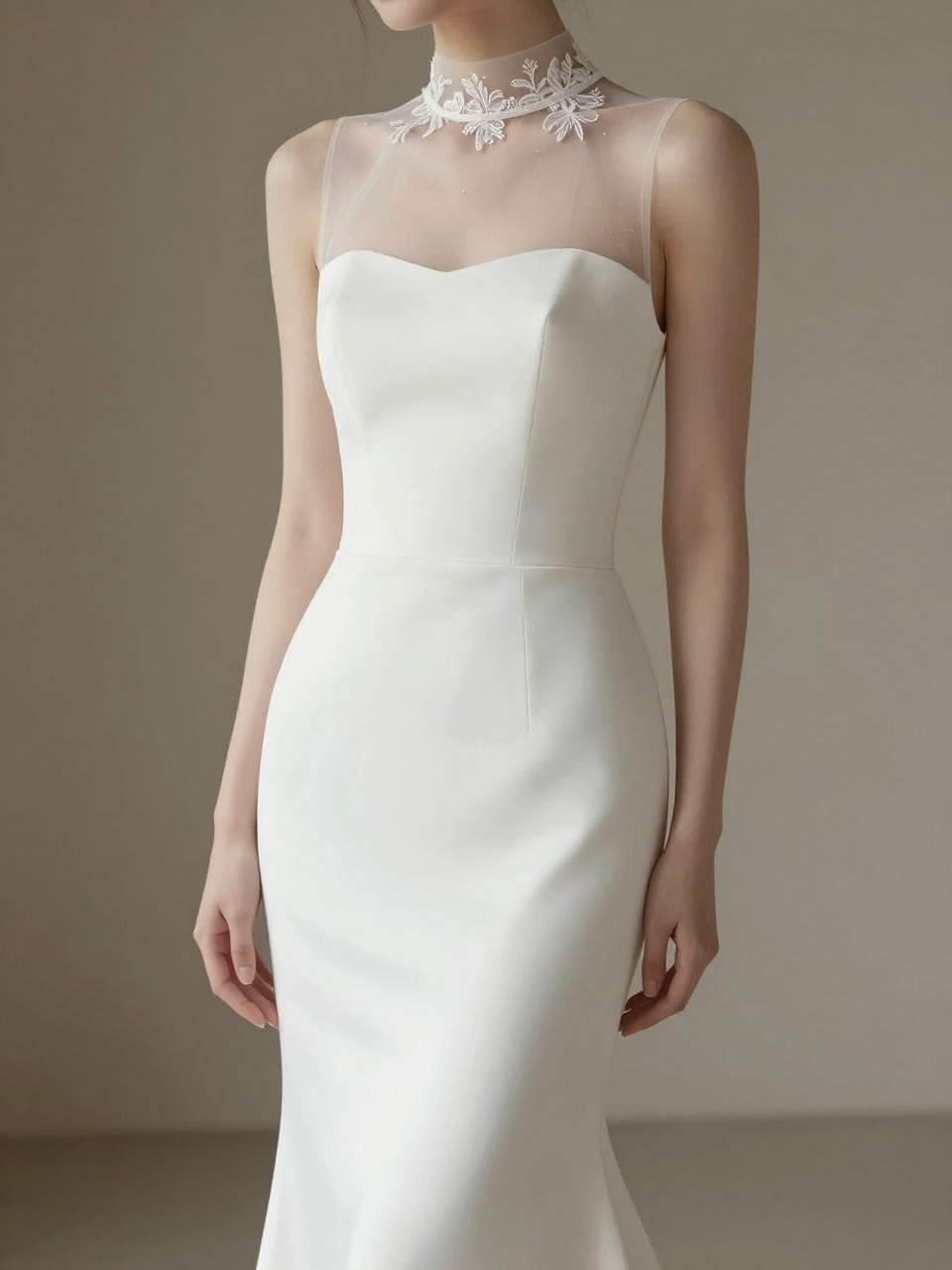 Image Prompt: A refined bridal editorial image of a sleeveless crepe wedding gown styled with a high neck illusion bolero. Show only from the neck down or from a side-back angle with the face completely hidden. The bolero has sheer fabric, delicate embroidery, and a graceful high neckline over a slim crepe silhouette. Use soft chapel lighting, elegant bridal posture, realistic fabric drape, luxury wedding magazine styling, no visible face, no text, no watermark. (no watermarks on images)