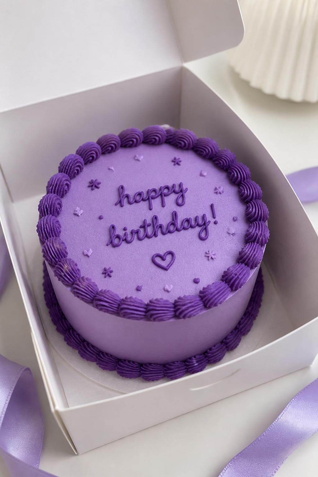 Image Prompt:
A cute monochrome purple birthday bento cake inside an open white cake box, smooth medium purple frosting, darker purple piped border, purple handwritten birthday text, tiny purple heart and star details, modern tone-on-tone styling, bright clean backdrop, realistic editorial dessert photography, no people, no hands, no faces, (no watermarks on images)