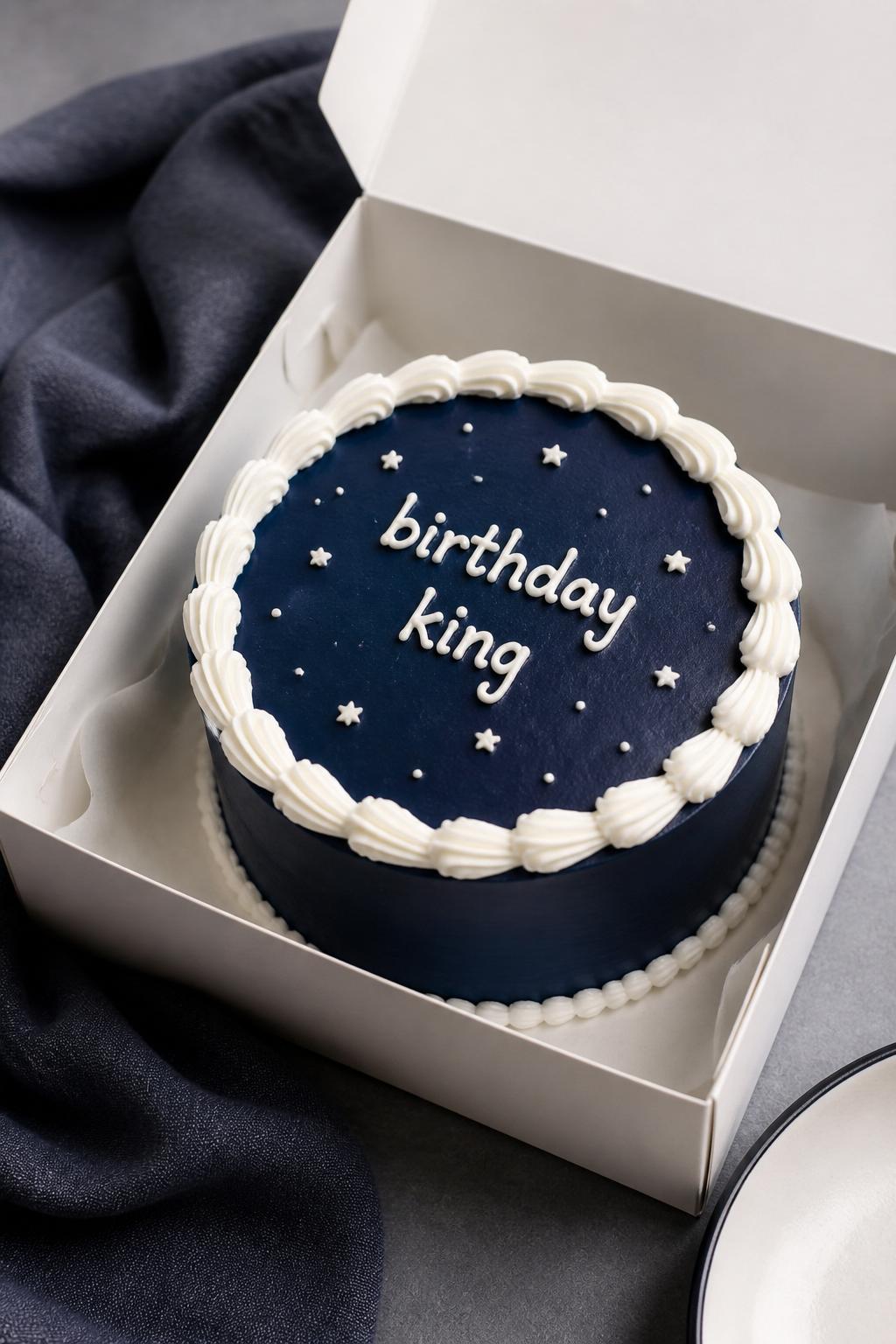 Image Prompt:
A lovely navy blue bento birthday cake for men inside an open white bento cake box, smooth deep navy frosting, white piped border, neat icing text reading “birthday king,” tiny white star and dot details, modern clean dessert styling, dark linen napkin nearby, realistic DSLR bakery photography, no people, no hands, no faces, no watermarks on images