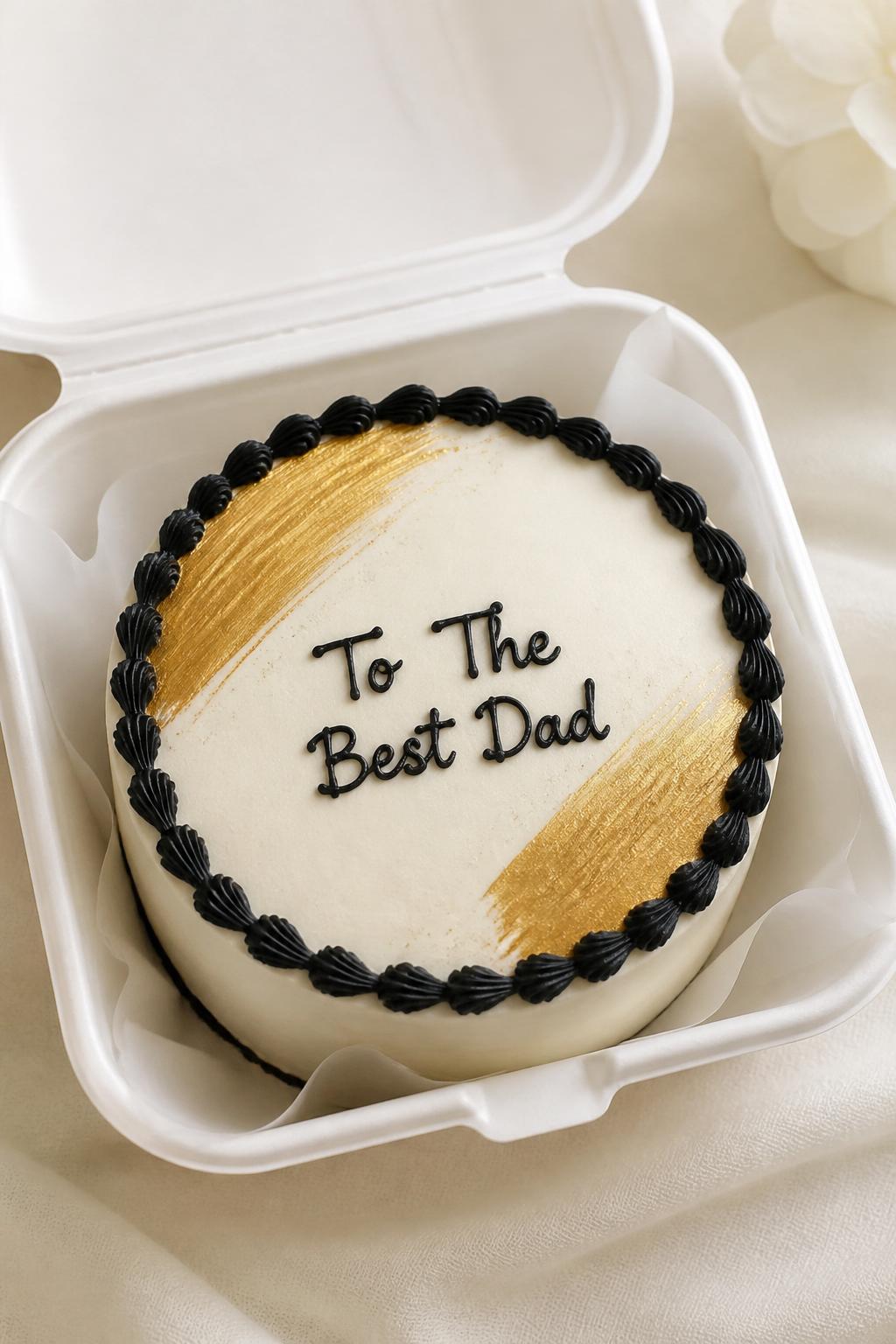Image Prompt:
An elegant Father’s Day bento cake inside an open white cake box, smooth ivory frosting, subtle gold brushstroke accents, neat black piped border, handwritten icing text reading “To The Best Dad,” classy refined dessert styling, clean soft background, realistic close-up bakery photography, no people, no hands, no faces, no watermarks on images