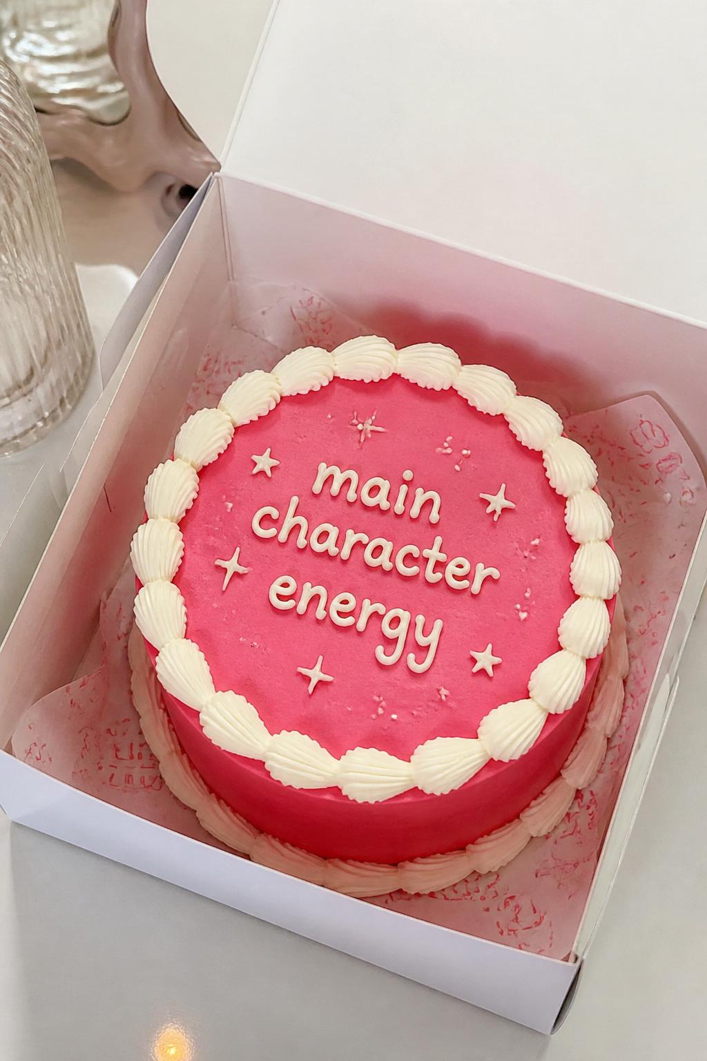 Image Prompt:
A funny trendy bento cake inside an open white cake box, smooth hot pink frosting, bold white piped border, handwritten icing text reading “main character energy,” tiny star doodles and sparkle details, playful modern dessert styling, bright editorial lighting, realistic bakery photography, no people, no hands, no faces, no watermarks on images