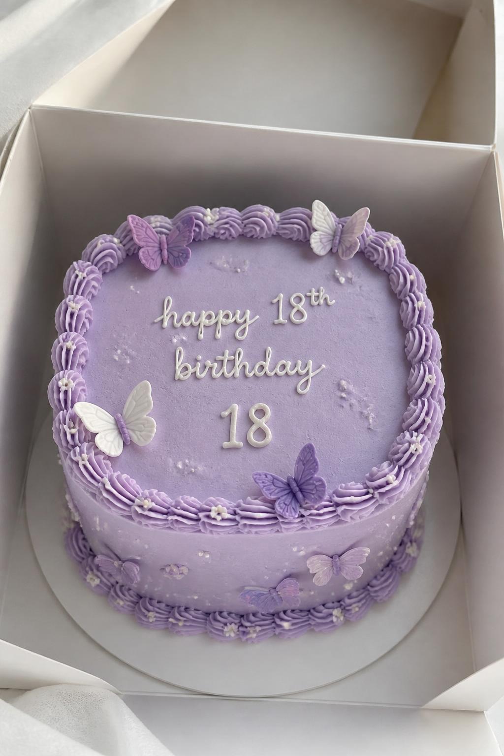 Image Prompt:
A cute butterfly themed 18th birthday bento cake inside an open white cake box, smooth pastel purple frosting, tiny lavender and white butterfly decorations, neat piped border, small icing number “18,” soft whimsical bakery styling, bright natural light, realistic close-up dessert photography, no people, no hands, no faces, no watermarks on images