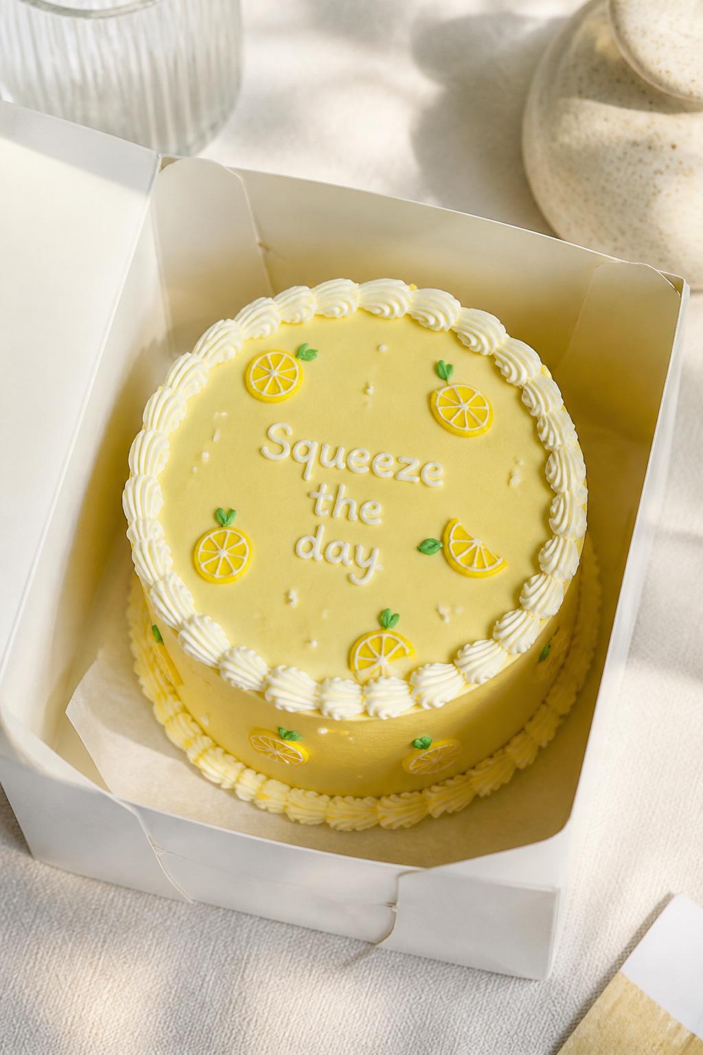 Image Prompt:
A cute lemon inspired yellow bento cake inside an open white cake box, smooth lemon yellow frosting, tiny lemon slice illustrations, white piped border, fresh playful bakery styling, bright natural light, soft clean backdrop, realistic editorial dessert photography, no people, no hands, no faces, no watermarks on images