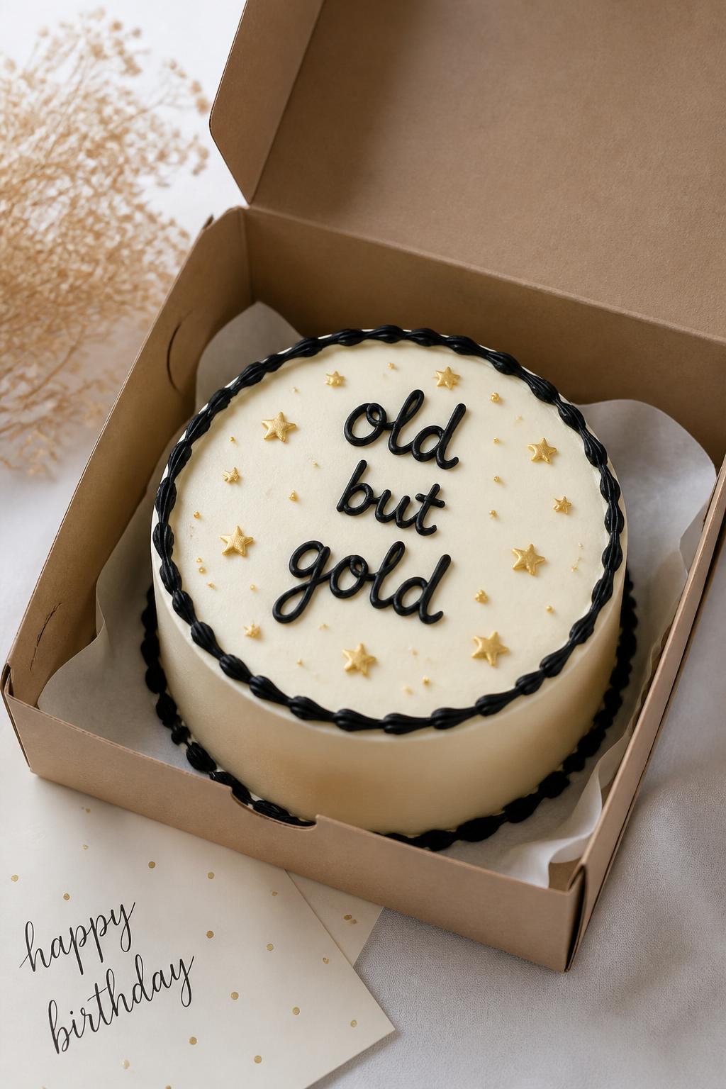 Image Prompt:
A funny bento birthday cake inside an open kraft bento cake box, smooth cream buttercream frosting, bold black handwritten icing text reading “old but gold,” tiny gold star details, neat black piped border, playful but clean birthday styling, soft natural light, realistic editorial bakery photography, no people, no hands, no faces, no watermarks on images
