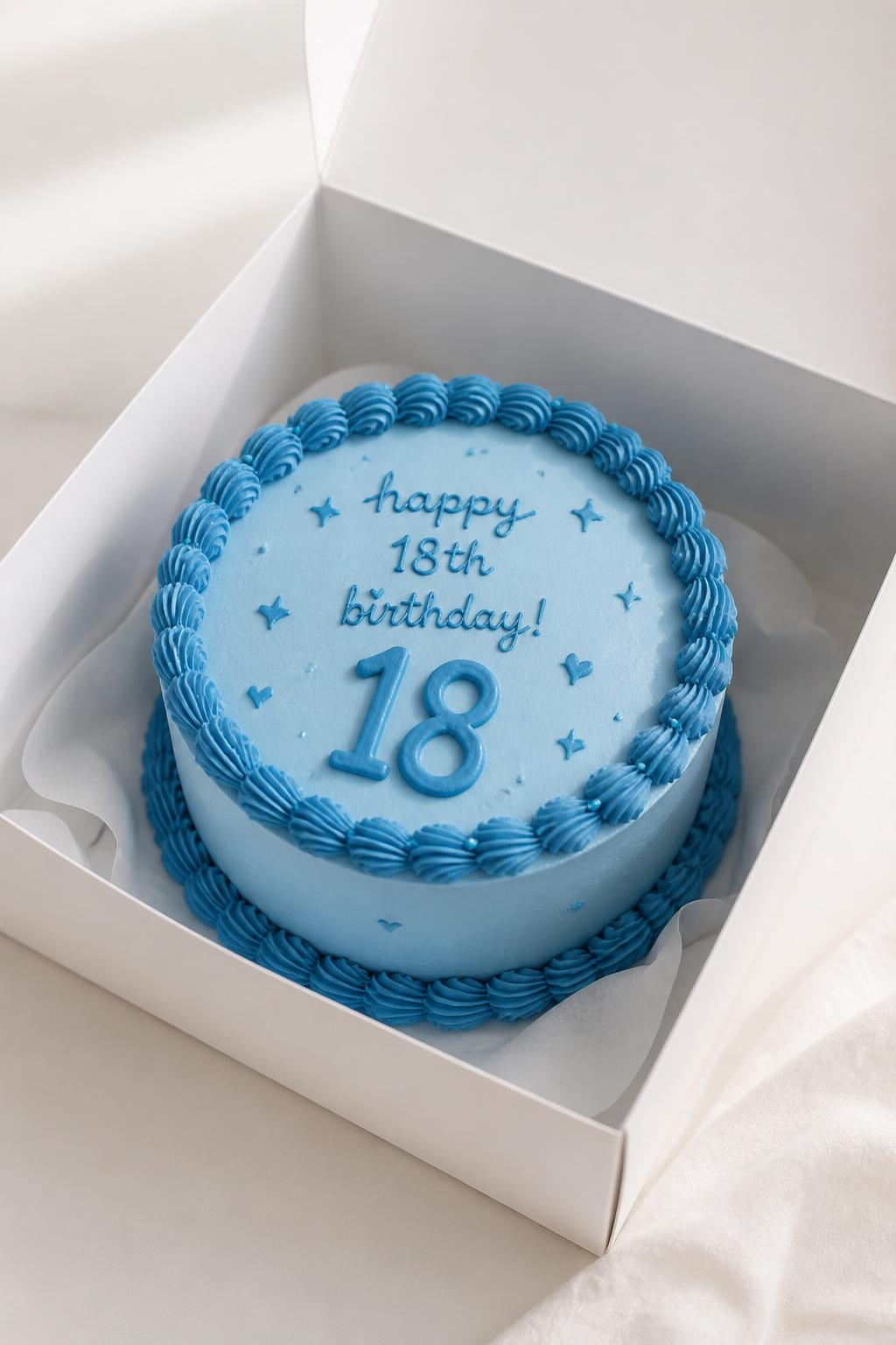 Image Prompt:
A beautiful monochrome blue 18th birthday bento cake inside an open white cake box, smooth baby blue frosting, darker blue piped border, blue handwritten birthday text, large icing number “18,” tiny blue heart and star details, modern tone-on-tone styling, bright clean backdrop, realistic editorial dessert photography, no people, no hands, no faces, no watermarks on images
