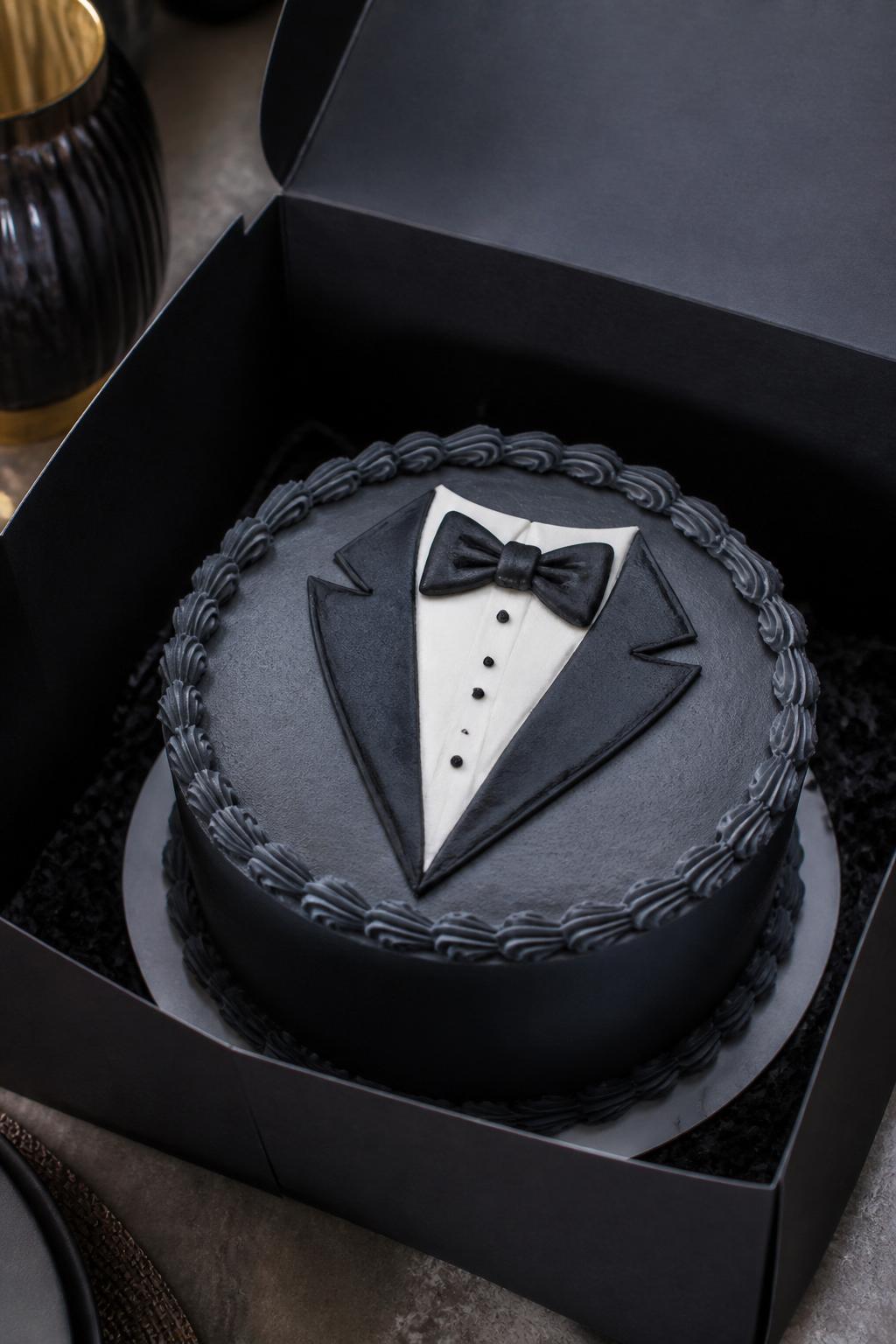 Image Prompt:
A gentleman suit inspired bento cake for men in an open black cake box, smooth charcoal gray frosting, simple icing design shaped like a tuxedo lapel and bow tie, small white shirt detail, neat piped border, classy celebration styling, realistic close-up bakery photography, no people, no hands, no faces, no watermarks on images