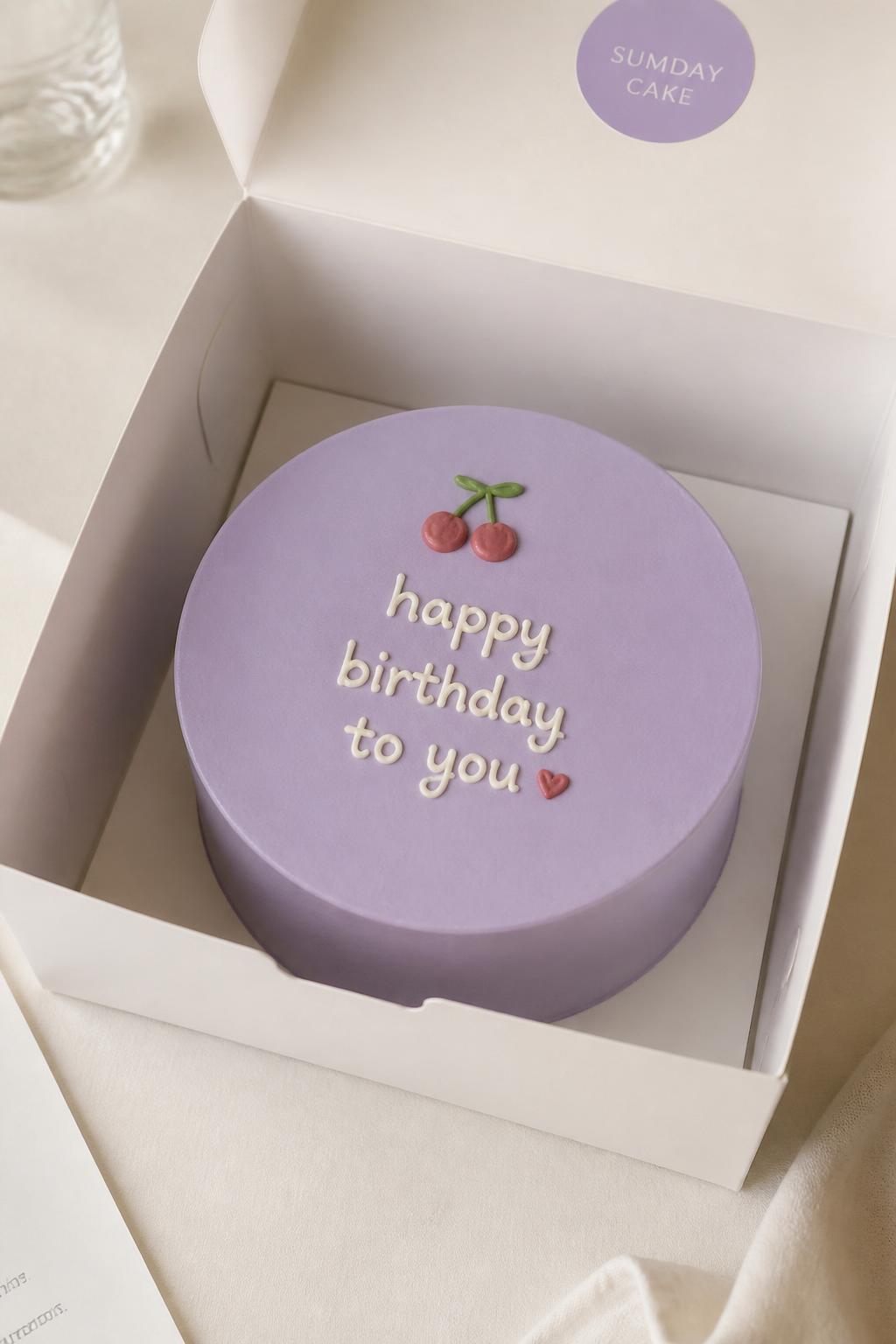 Image Prompt:
A modern Korean style lavender bento cake in a white cake box, smooth pale purple frosting, clean finish, tiny cherry or heart detail, simple handwritten icing message, minimal cute styling, soft neutral background, realistic editorial bakery photo, no people, no hands, no faces, (no watermarks on images)