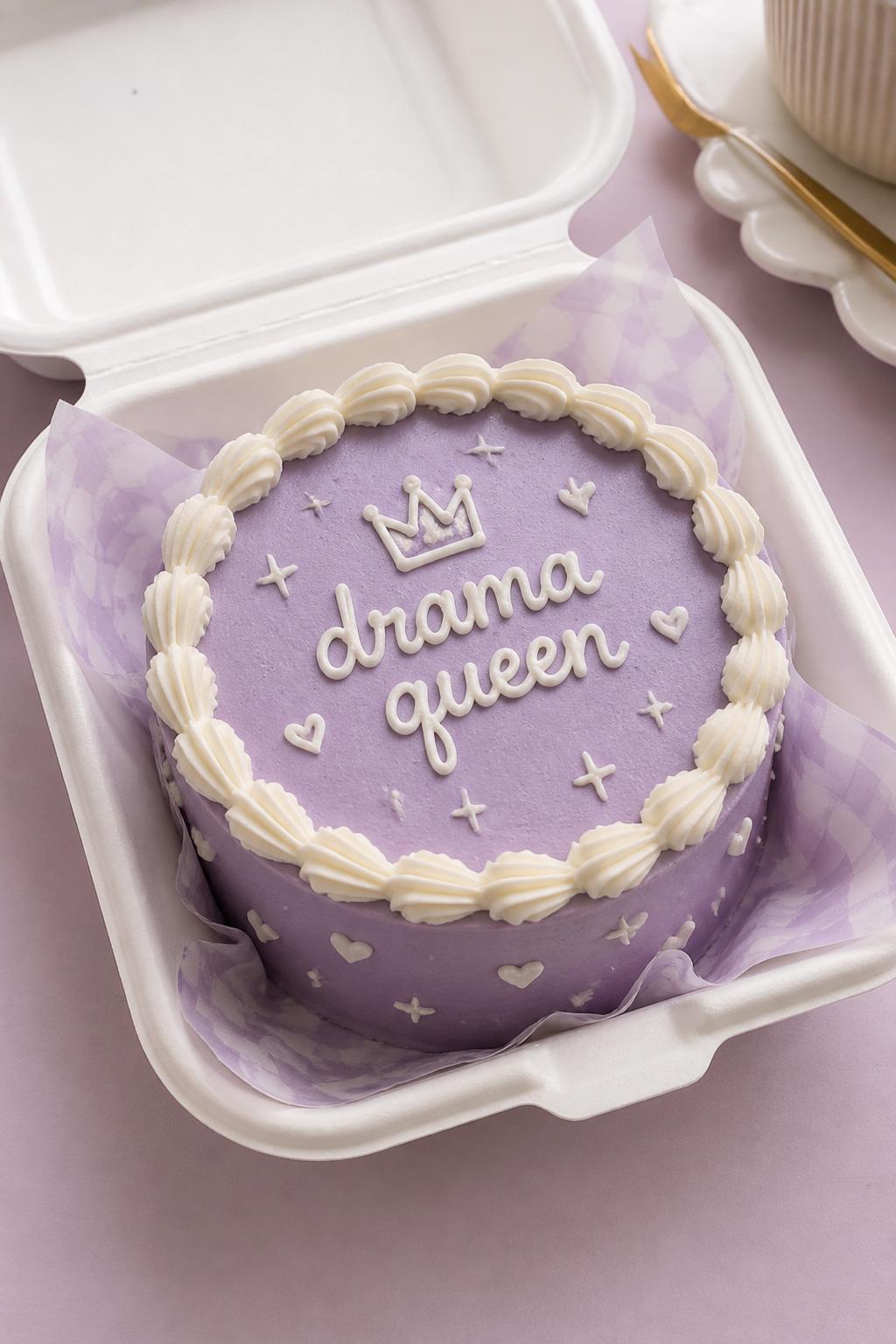 Image Prompt:
A funny cute bento cake in an open white bento box, lavender buttercream frosting, neat white piped border, handwritten icing text reading “drama queen,” tiny crown doodle, little star and heart accents, playful feminine dessert styling, soft pastel background, realistic editorial bakery photography, no people, no hands, no faces, no watermarks on images