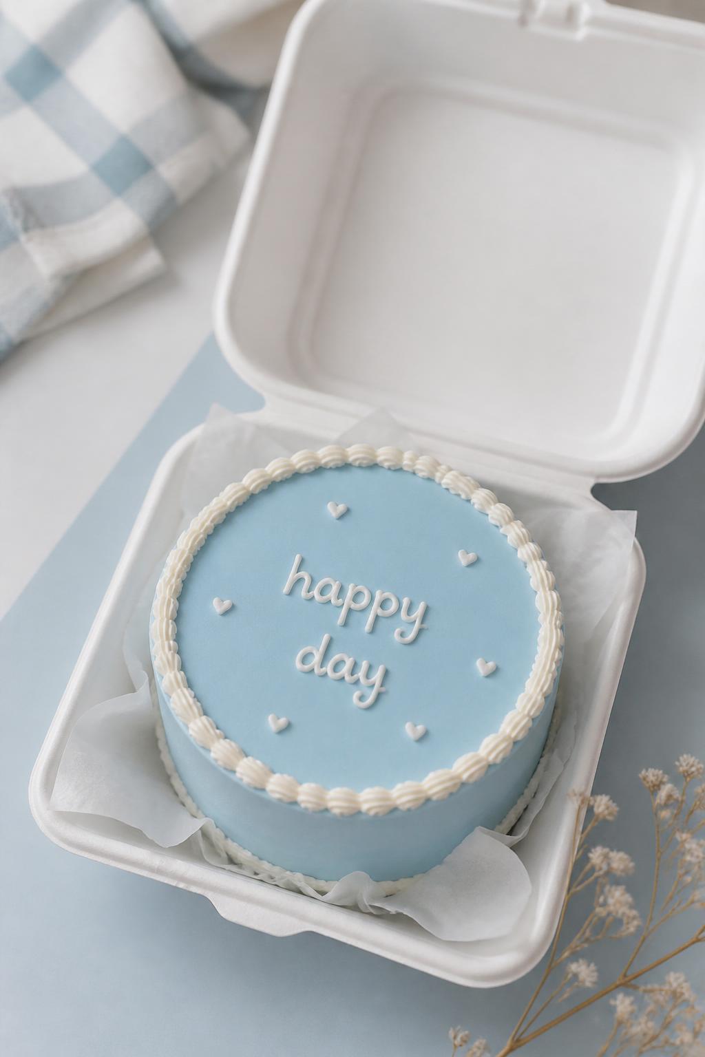 Image Prompt:
A beautiful minimal baby blue bento cake inside an open white bento cake box, smooth baby blue buttercream frosting, neat white piped border, short handwritten icing text that says “happy day,” tiny white heart details, clean modern styling, soft natural light, pastel background, editorial bakery photography, realistic dessert styling, no people, no hands, no faces, (no watermarks on images)