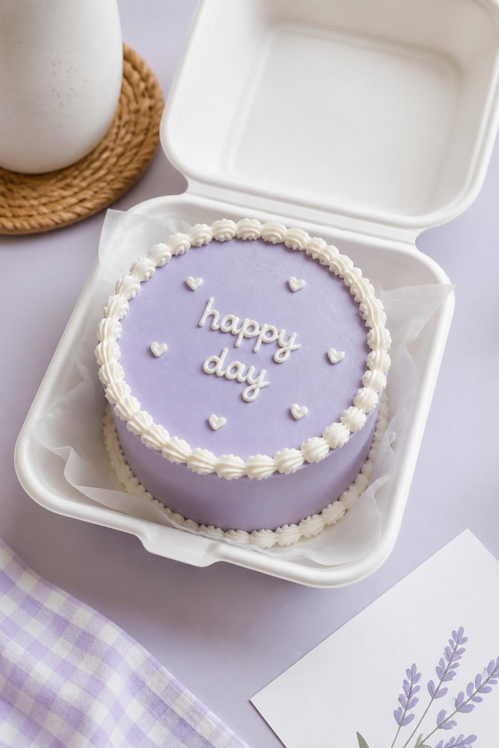 Image Prompt:
A cute minimal lavender bento cake inside an open white bento cake box, smooth lavender buttercream frosting, neat white piped border, short handwritten icing text that says “happy day,” tiny white heart details, clean modern styling, soft natural light, pastel background, editorial bakery photography, realistic dessert styling, no people, no hands, no faces, (no watermarks on images)