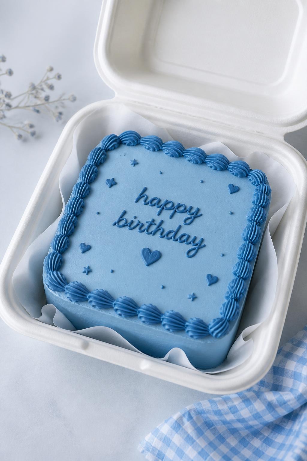 Image Prompt:
A beautiful monochrome blue birthday bento cake inside an open white cake box, smooth blue frosting, darker blue piped border, blue handwritten birthday text, tiny blue heart and star details, modern tone-on-tone styling, bright clean backdrop, realistic editorial dessert photography, no people, no hands, no faces, (no watermarks on images)