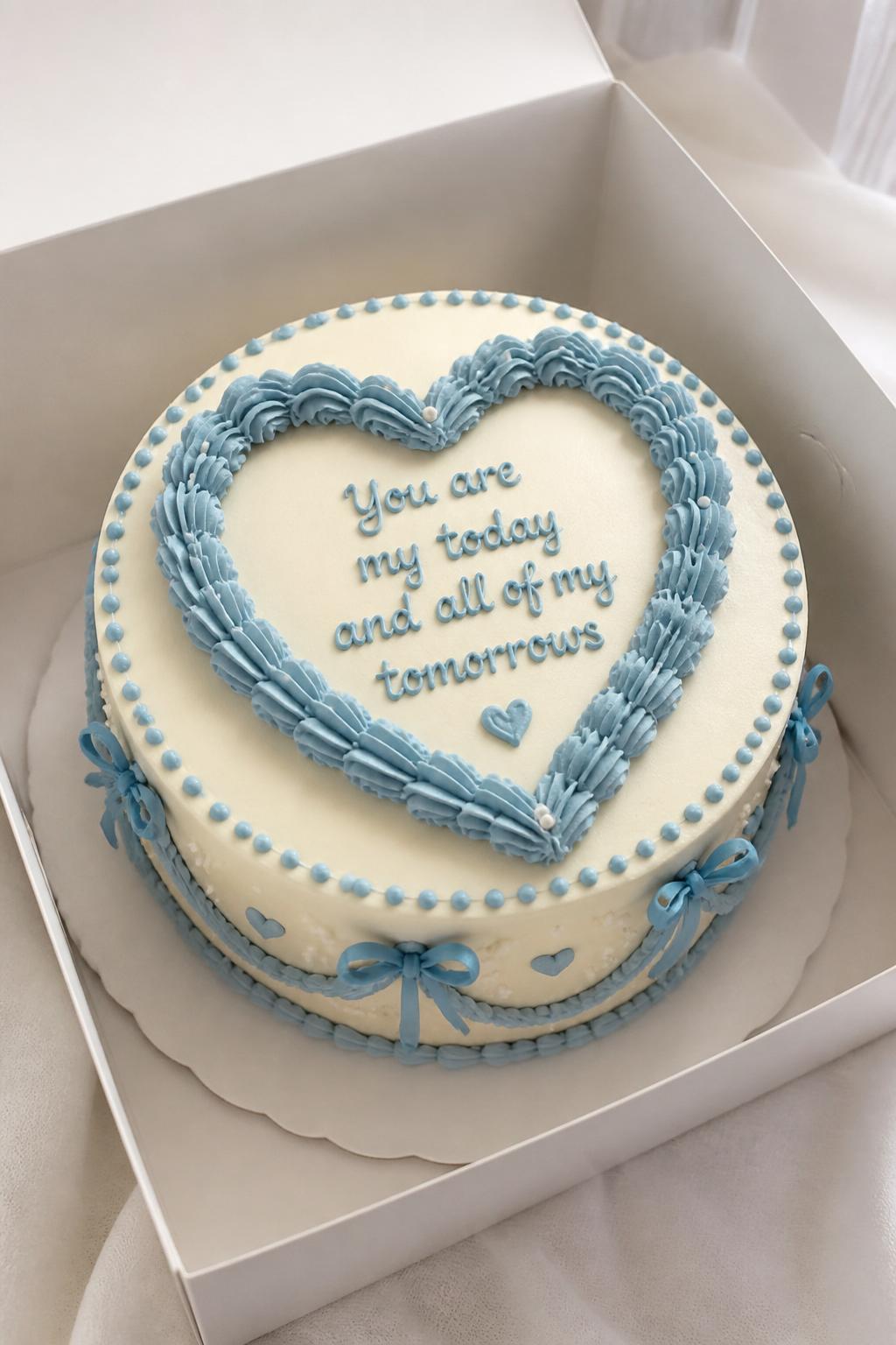 Image Prompt:
A beautiful blue heart frame bento cake inside an open white cake box, smooth cream and pale blue frosting, a piped blue heart frame around the center, neat message inside the heart, tiny dot border, soft romantic styling, realistic dessert photography, no people, no hands, no faces, (no watermarks on images)
