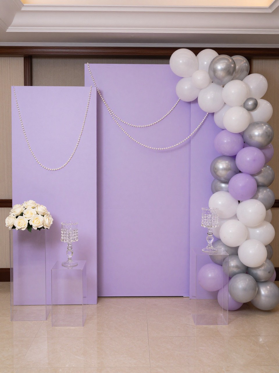 Image Prompt:
A single realistic editorial-style photo of a lavender quinceañera backdrop with pale lavender curved panels, pearl garlands draped neatly across the panels, white and silver balloon accents, ivory roses, crystal candle holders, clear plinths, elegant indoor venue, no people, no faces, soft flattering lighting, realistic upscale event photography, no text, no watermark.