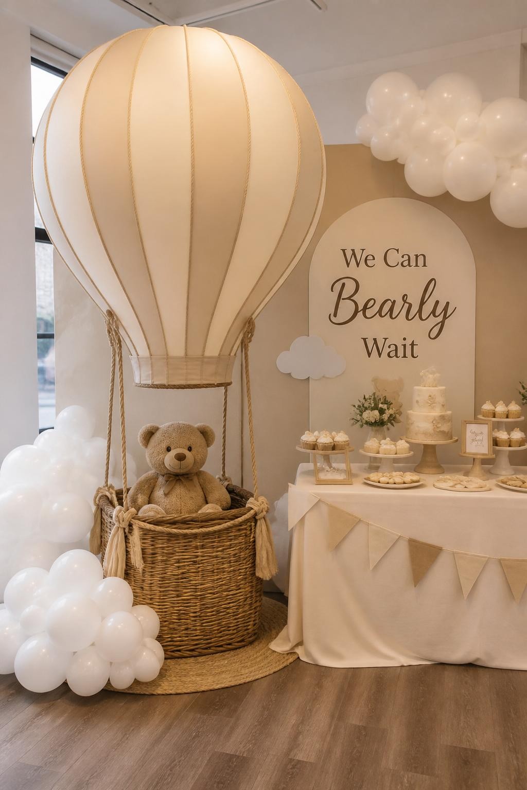 Image Prompt:
A realistic single-image baby shower display with a plush teddy bear sitting in a small wicker hot air balloon basket, large cream balloon arrangement above it shaped like a hot air balloon, soft clouds made from white balloons, beige and ivory backdrop, sign reading “We Can Bearly Wait,” baby shower dessert table beside the display, no people, no faces, bright indoor event space, editorial decor photography, realistic basket and balloon textures, no watermarks on images