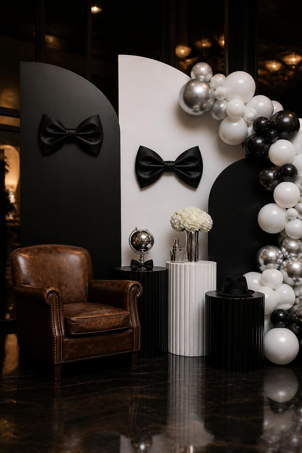 Image Prompt:
A single realistic photo of a classy gentleman-inspired Father’s Day backdrop with matte black and white curved panels, black bow tie props, white and silver balloon clusters, sleek pedestal stands, leather accent chair, warm indoor evening setting, no people, no faces, realistic upscale party photography, no readable text, no watermark.