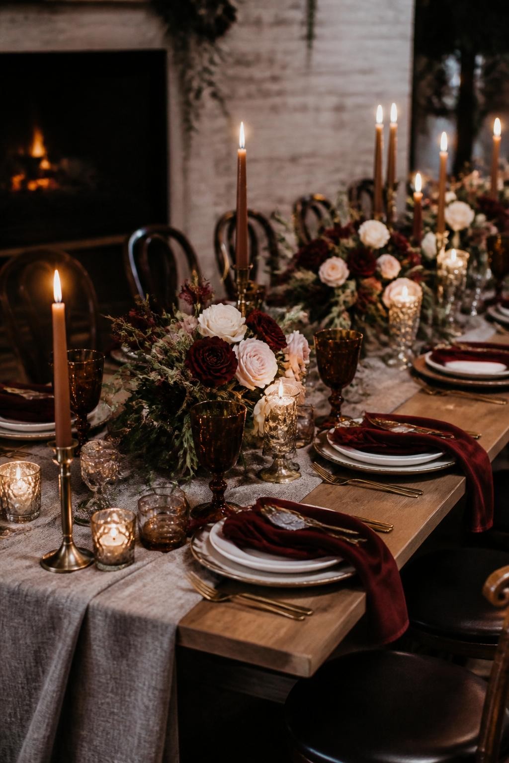 Realistic DSLR photo of a late fall wedding reception table styled with deep velvet napkins, wool table runners, brass candlesticks, burgundy and cream floral centerpieces, dark wood chairs, amber glassware, and warm candlelight, cozy indoor wedding dinner setting, refined editorial style.