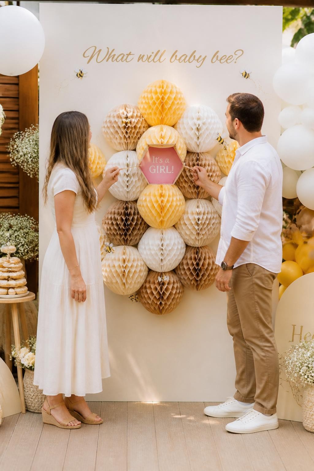 A realistic photo of a creative gender reveal wall with honeycomb paper shapes, soft yellow, cream, tan, and white colors, tiny bee accents, parents pulling one center tab from a honeycomb display to reveal a hidden baby message in one color, warm backyard party light, editorial lifestyle photography