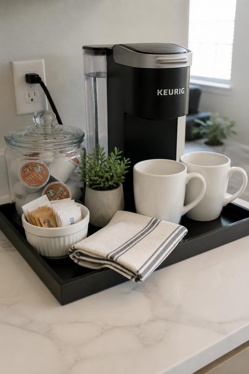 A realistic DSLR photo of a compact coffee bar arranged on a small black serving tray, coffee machine at the back, two white ceramic mugs, glass jar of coffee pods, small bowl of sugar packets, tiny faux plant, folded linen-style napkin, bright kitchen countertop, realistic natural daylight, neat apartment coffee corner, no people.