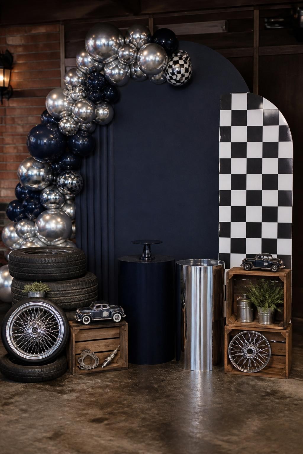 Image Prompt:
A single realistic editorial-style photo of a Father’s Day backdrop inspired by classic cars, with a dark navy panel, chrome silver balloon accents, black and white checkered details, vintage garage-style props, small wooden crates, warm indoor garage party setting, no people, no faces, realistic event photography, no readable logos, no text, no watermark.