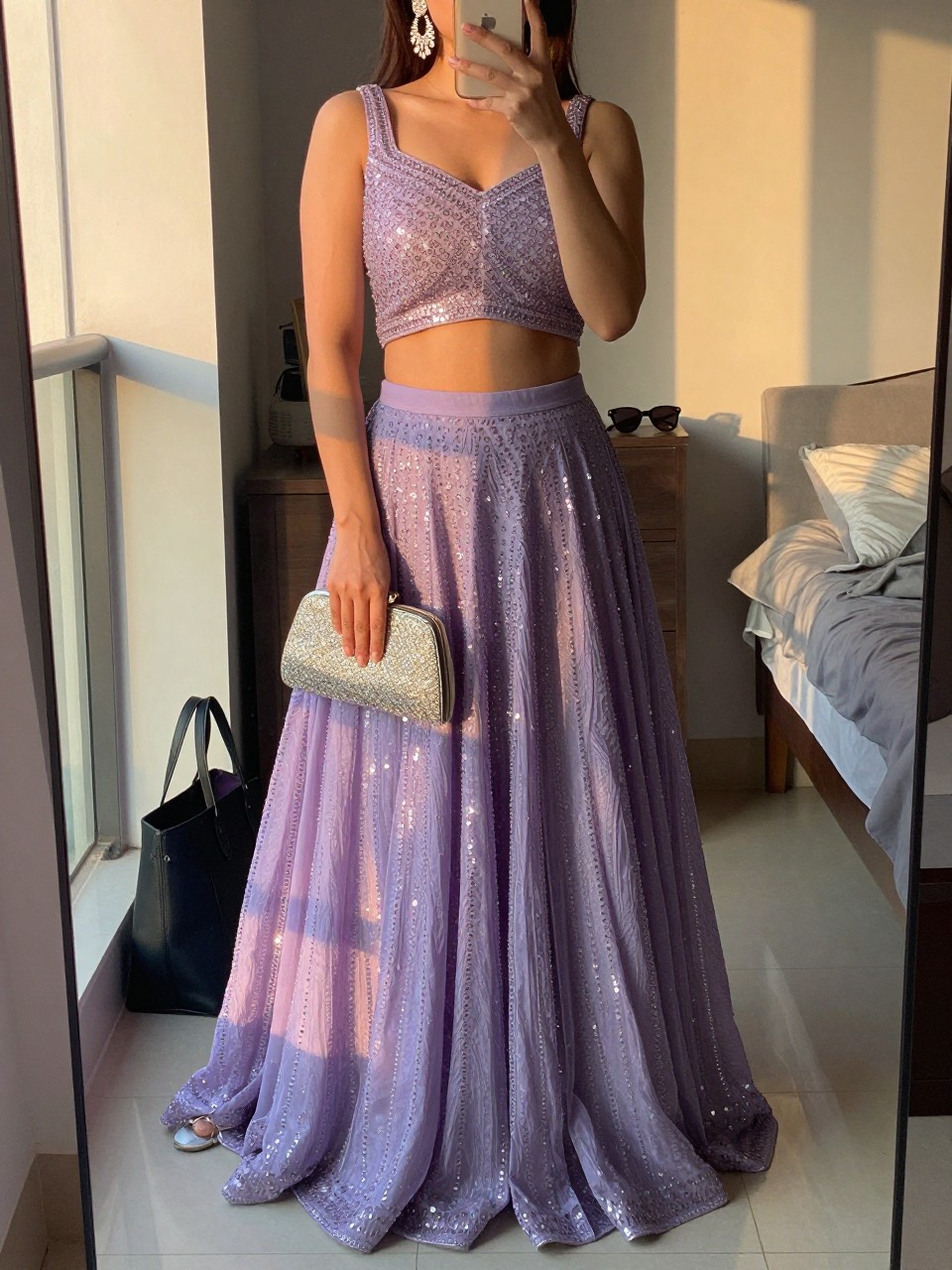 Image prompt
mirror selfie of a woman wearing a lavender lehenga with delicate sequins and a matching choli top, silver chandelier earrings, silver heeled sandals, and an embellished clutch, holding a phone in front of a mirror, cropped at NECK so face doesn't show, with a natural casual selfie pose, in a city apartment, evening golden hour, including small lived-in details like a tote bag on the floor, sunglasses on a dresser, or soft bedding in the background, latest iPhone photo quality.