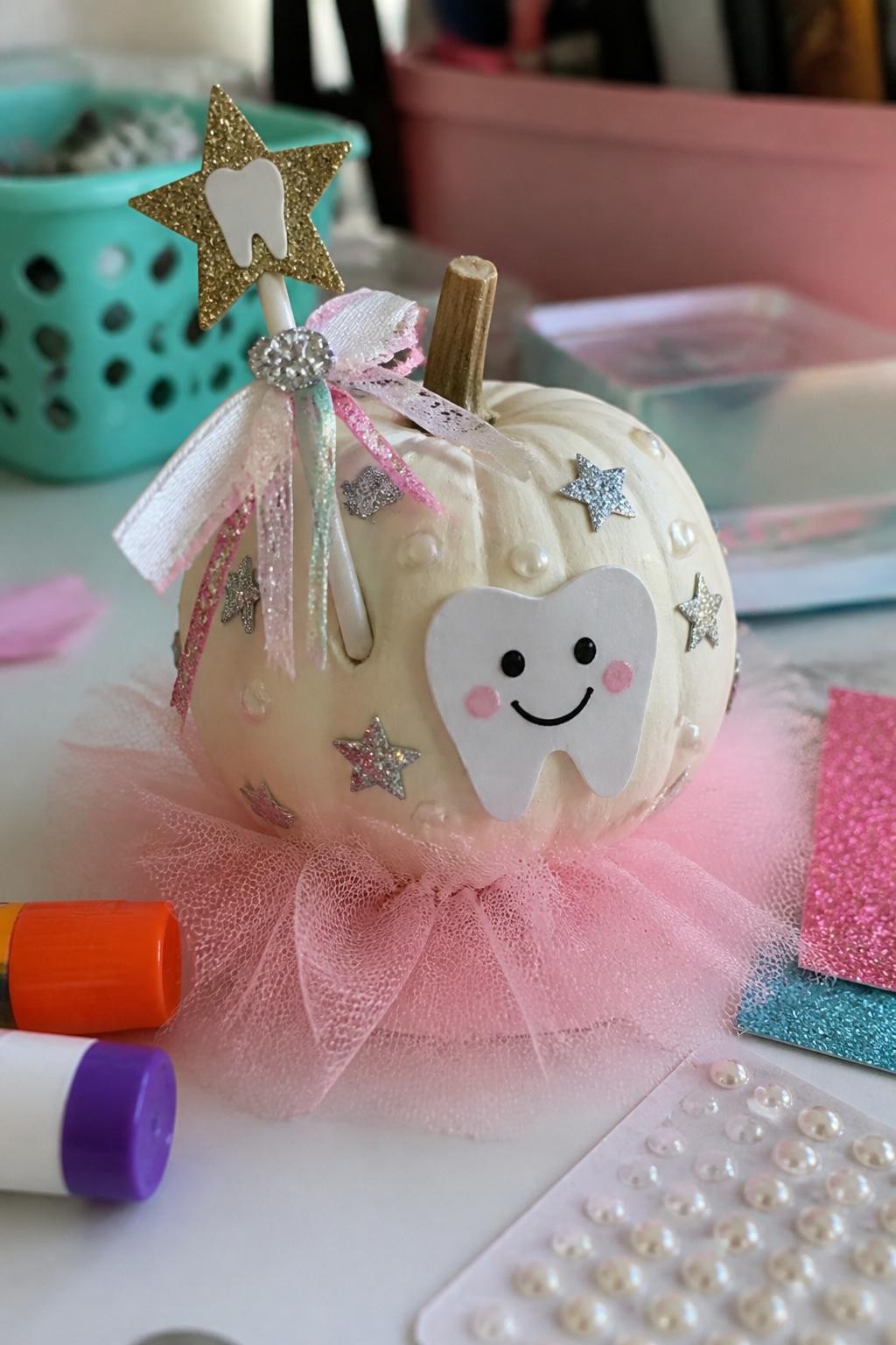 Image Prompt: A realistic DSLR photo of a small white pumpkin decorated with a sparkly tooth fairy wand theme, featuring tiny silver stars, a gold paper wand attached near the stem, a smiling tooth face, pearl sticker dots, pastel ribbons, and a soft pink tulle base, photographed on a bright kids craft table with glitter paper, glue sticks, and warm daylight.
