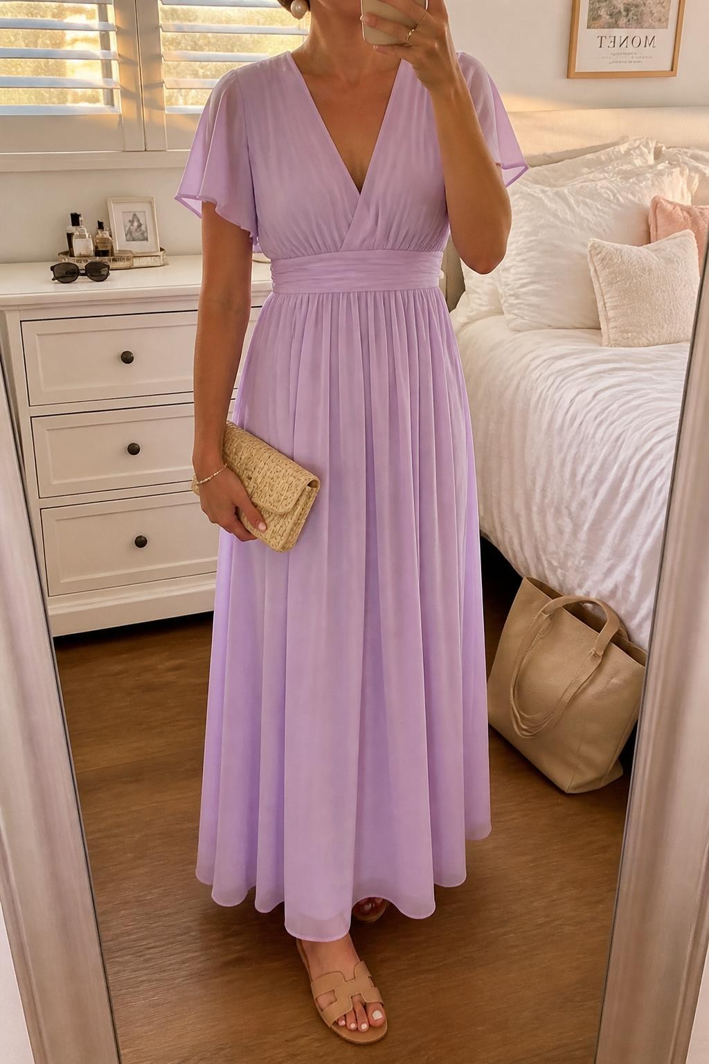 Image prompt
mirror selfie of a woman wearing a pastel lavender chiffon maxi dress with a flowy skirt, pearl stud earrings, nude flat sandals, and a small woven clutch, holding a phone in front of a mirror, cropped at NECK so face doesn't show, with a natural casual selfie pose, in a feminine-themed bedroom, evening golden hour, including small lived-in details like a tote bag on the floor, sunglasses on a dresser, or soft bedding in the background, latest iPhone photo quality.