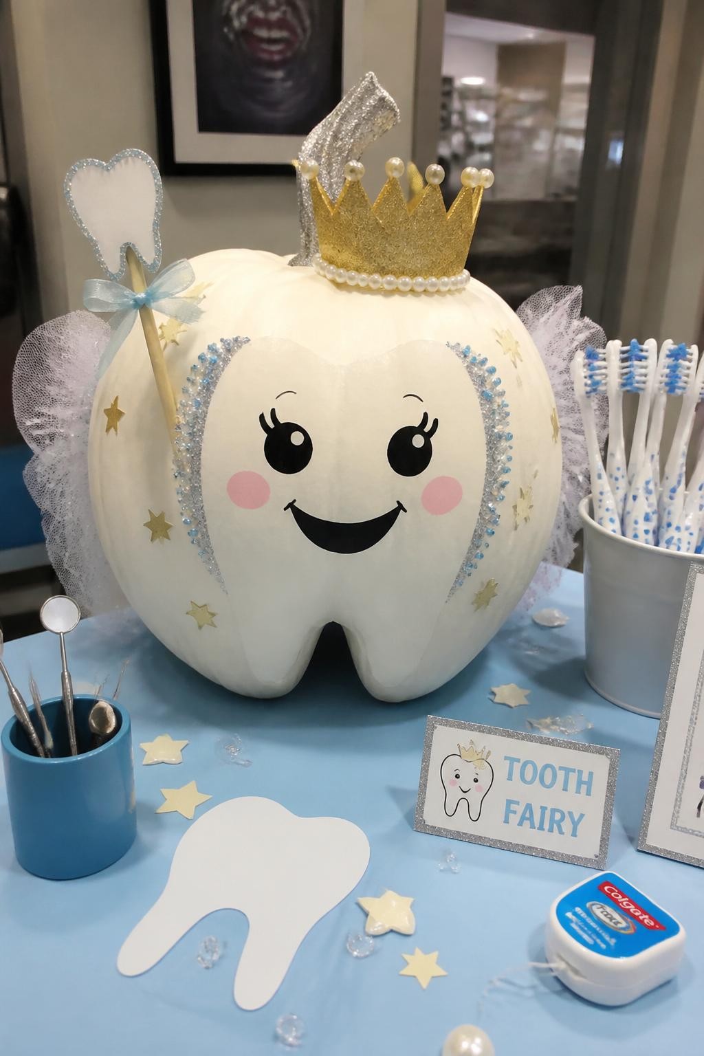 Image Prompt: A realistic DSLR photo of a white pumpkin decorated with a large smiling tooth wearing a tiny crown, silver glitter accents, blue pearl stickers, gold star details, and soft painted cheeks, styled on a dental office display table with toothbrushes, dental floss, mini mirrors, and bright clean lighting, cute tooth fairy pumpkin contest idea.
